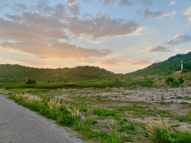一张以日落为背景的道路的照片，有一个人骑着自行车沿着日落为背景的道路行驶。图片下载