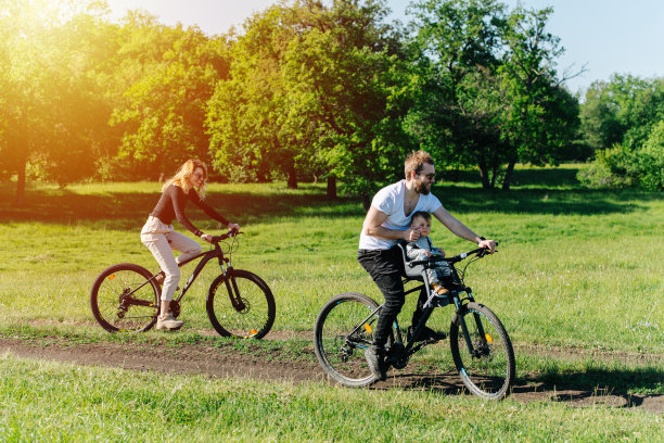 微笑的妈妈，爸爸和他们的宝宝在一个晴朗的日子里骑在乡村里图片下载