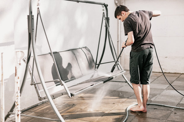 一个年轻人用水壶洗花园秋千。图片下载