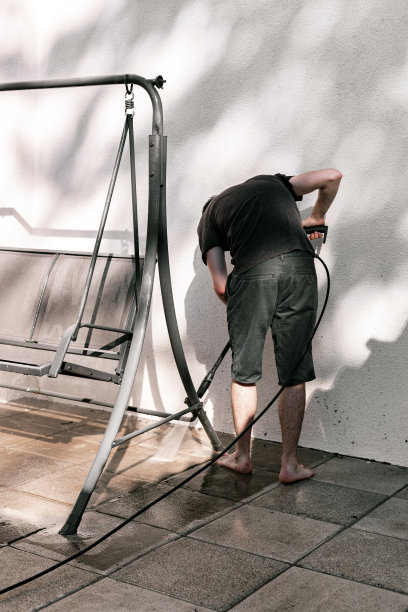 一个年轻人用水壶洗花园秋千。图片下载