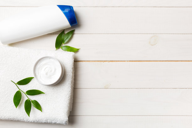 化妆洗发水瓶子模型和毛巾放在彩色的桌子上。浴室背景，手部和身体护理的卫生间配件图片下载