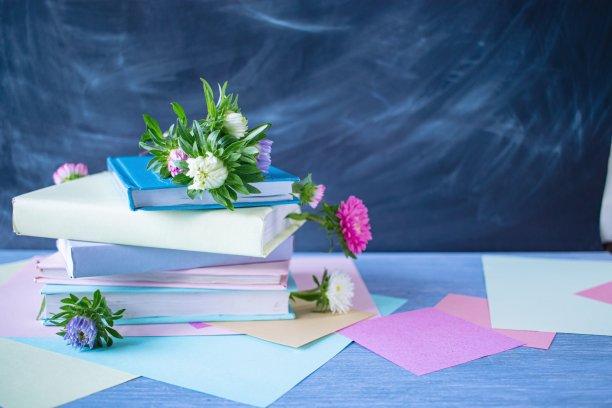 木桌上有一摞带花书签的书，背景是黑板、纸图片下载