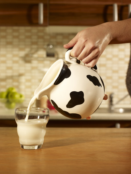 女人手倒一杯牛奶。图片下载