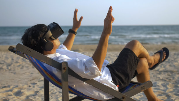 亚洲男人戴VR眼镜在沙滩上放松图片下载