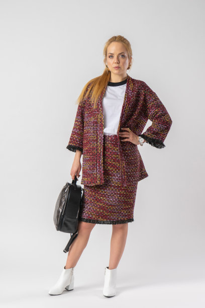 一个年轻的金发女郎，穿着一套休闲温暖的办公室装，手里拿着一个包。图片下载