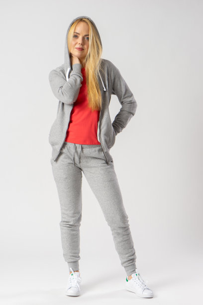 一个年轻的金发女郎穿着灰色运动服，红色背心和白色运动鞋。图片下载