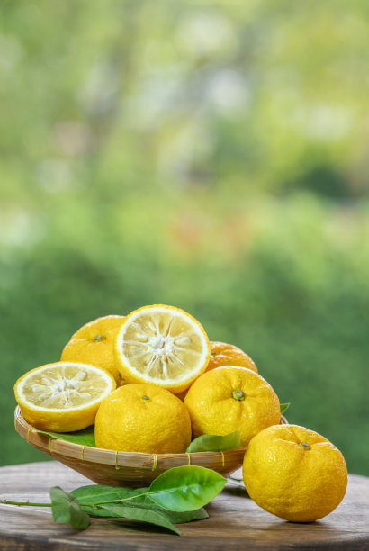 高知黄柚子在绿色自然模糊背景，柚子橙水果在木篮子在模糊绿色背景。图片下载