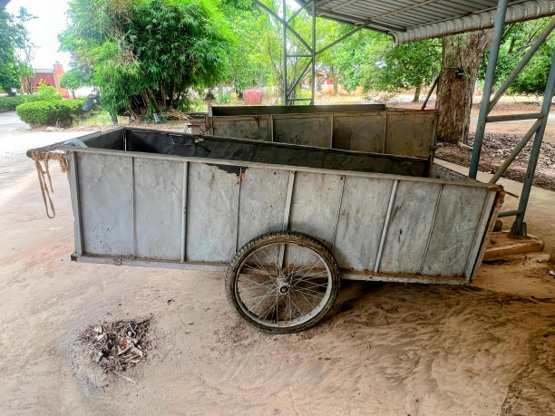 一幅金属小推车带着自行车轮子的照片，泥土上有一辆金属小推车带着轮子。图片下载