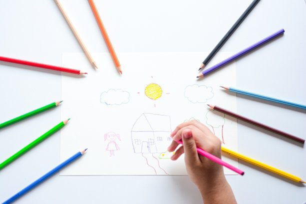 贴近孩子的手，用彩色铅笔在白纸上画画。图片下载