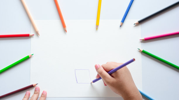 贴近孩子的手，用彩色铅笔在白纸上画画。图片下载