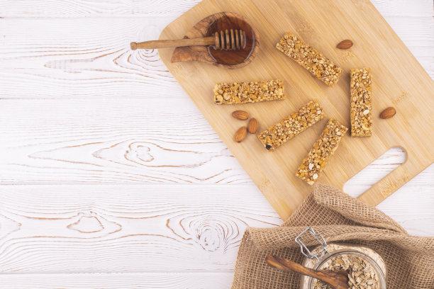 白色木桌上的麦片什锦棒，上面放着坚果和蜂蜜。健康的甜点小吃。图片下载