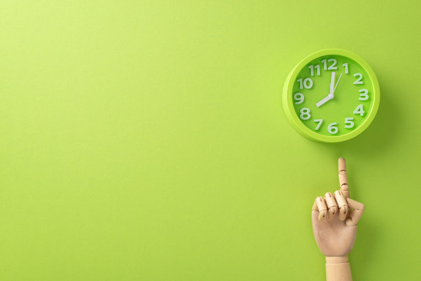 参与教育的过程中，这张俯视图的照片，在孤立的浅绿色背景上，玩具手指向教室的时钟。利用文本或促销信息的复制空间图片下载