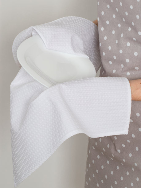 一位年轻女子用厨房毛巾擦拭白色瓷盘图片下载