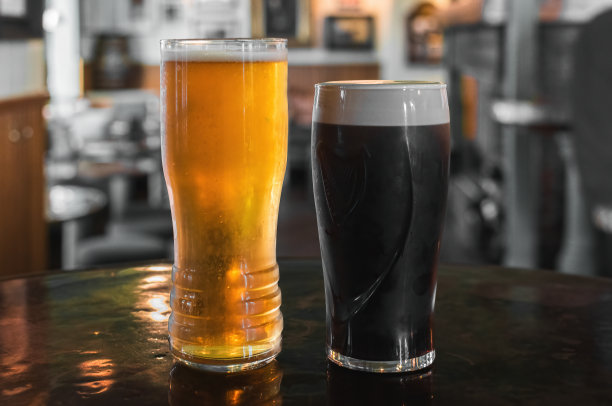 一杯黑啤酒和一杯淡啤酒在酒吧的桌子上图片下载