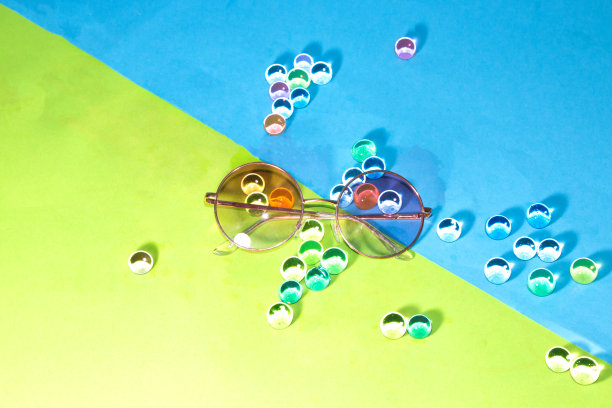 绿蓝色背景的太阳镜，3d透明彩色球，创意夏季概念图片下载