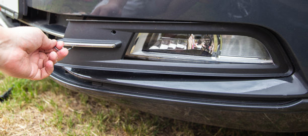 一名汽车修理工从一辆客车上取下雾灯来替换灯泡(特写)图片下载