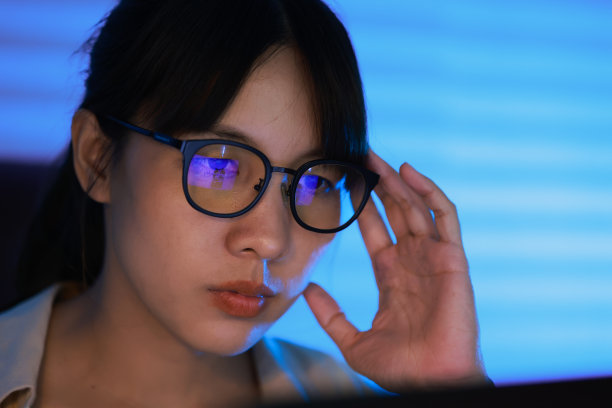 一个戴着眼镜的年轻漂亮女人的特写，她正在用笔记本电脑工作图片下载