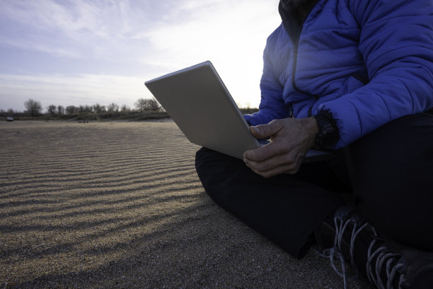 人与自然。男人在海边用笔记本电脑工作。本空间图片下载
