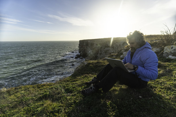 人与自然。男人在海边用笔记本电脑工作。本空间图片下载
