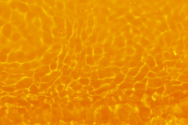 金色水彩与涟漪在表面上。散焦模糊透明黄色透明平静水面纹理与飞溅和泡沫。水波与闪亮的图案纹理背景。图片下载