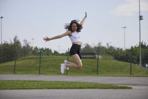 戴着眼镜的黑发美女在公园里跳来跳去图片下载