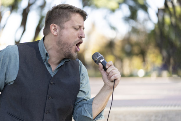 音乐家在街上唱歌的特写，他的手拿着麦克风图片下载
