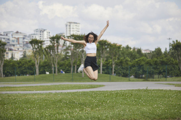 戴着眼镜的黑发美女在公园里跳来跳去图片下载