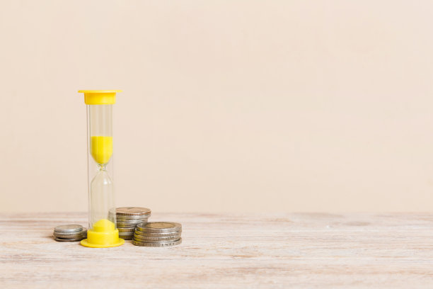 最后期限和时间是金钱概念与沙漏和美国硬币的货币。沙钟为节约时间的概念图片下载