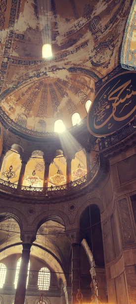 伊斯坦布尔圣索菲亚大教堂的内部展开，展示了一个迷人的场景，华丽的装饰，拱门和从窗户倾泻而出的天堂般的光晕。垂直的照片。图片下载