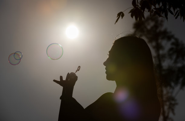 年轻女子玩泡泡棒的剪影。图片下载