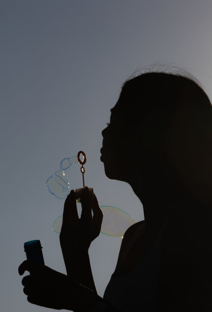 年轻女子玩泡泡棒的剪影。图片下载