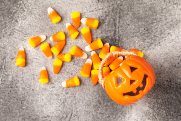 黑色背景的万圣节糖果。咖啡玉米和沙扎头骨。万圣节的节日背景有南瓜南瓜灯、玉米糖和装饰品。前视图。平的。放文字的地方。图片下载