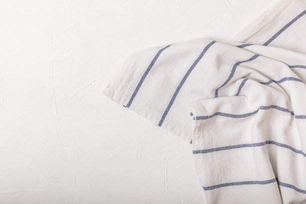 新的朴素图案的厨房毛巾折叠在一个有质感的桌子上。厨房用具。厨房毛巾或餐巾纸。文本的复制空间。放文字的地方。桌布。图片下载