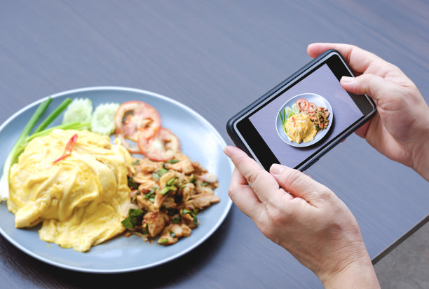 一名女子用智能手机拍摄木桌上的亚洲街头小吃图片下载