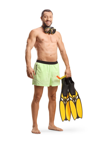 穿着泳装，戴着潜水面罩的健美男子站在那里，拿着浮潜鳍图片下载