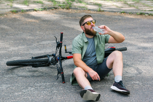 骑自行车的人可以在自行车附近休息，在森林里休息，在冒险锻炼中放松能量，喝一瓶水补水，在森林里享受健康。骑自行车的大胡子男子图片下载