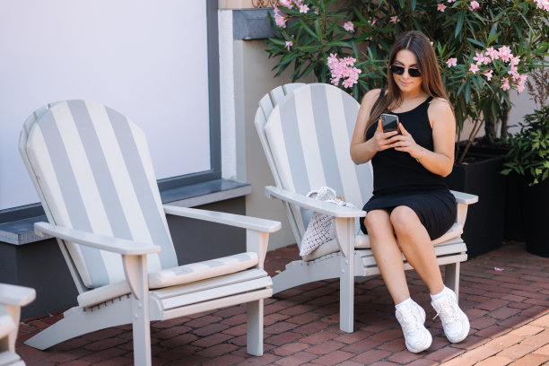 有魅力的女人用照片坐在户外的椅子上。花卉背景图片下载
