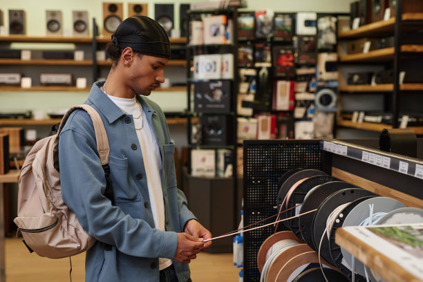 侧视图黑人年轻人在商店里为音乐器材挑选电线图片下载
