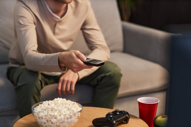 一个面目全非的人拿着遥控器在家看电视图片下载