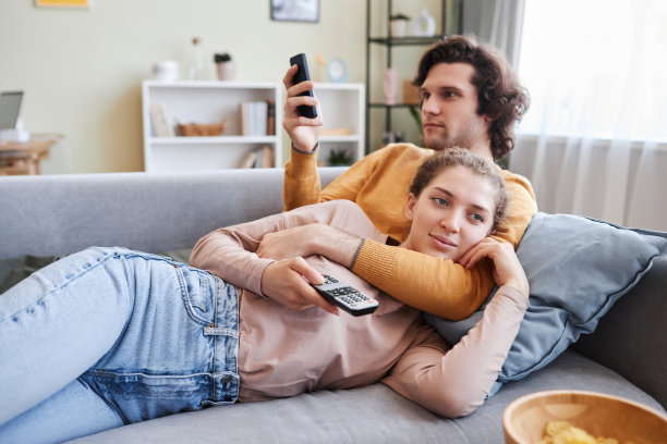 情侣依偎在家里的沙发上一起看电视图片下载