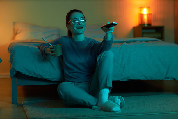 微笑的女人拿着遥控器在家看电视图片下载