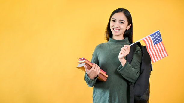 一个漂亮的亚洲女大学生拿着她的书和美国国旗。交换学生图片下载