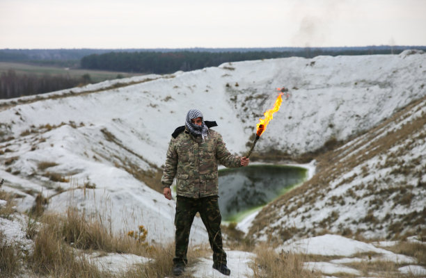 士兵手持火把。穿着迷彩服，戴着格子头巾的男人。人在山峡。沙漠中白色的山丘和干燥的草地。图片下载