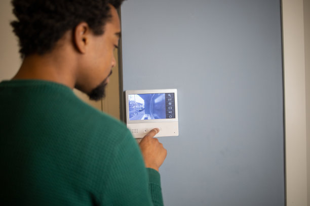一个年轻人用墙上的装置调节家里的温度图片下载