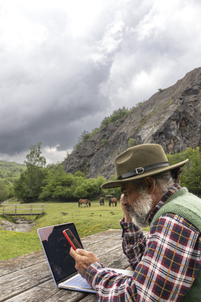 自由旅行者与胡子和帽子的任何地方工作在线使用笔记本电脑和享受山景图片下载