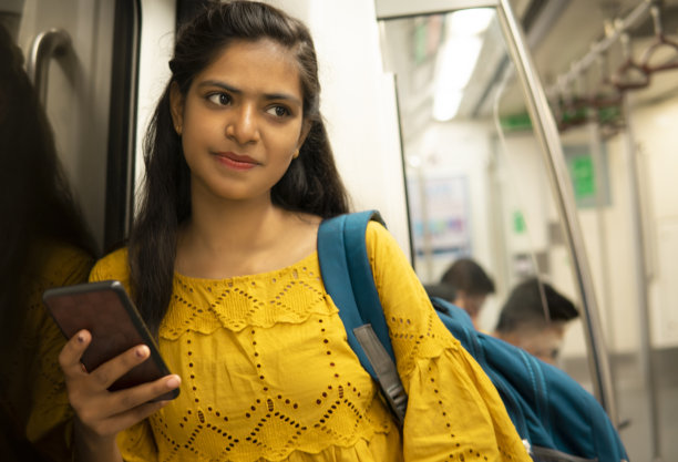 印度女人在地铁里用智能手机思考的特写。图片下载