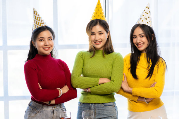 三个漂亮的亚洲女孩戴着派对帽，穿着五颜六色的服装庆祝自己的生日。图片下载