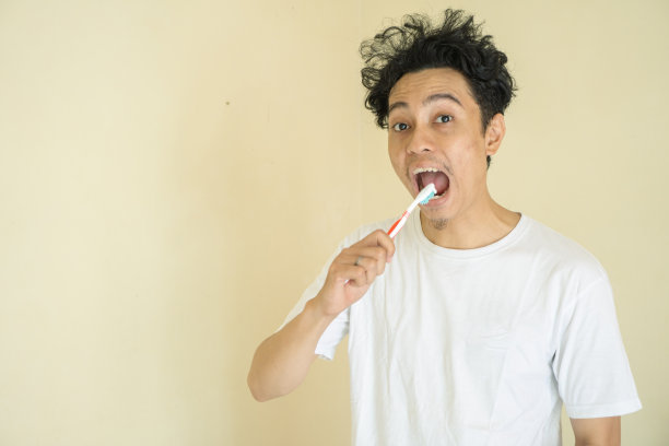 年轻卷曲的头发早上刷牙。图片下载