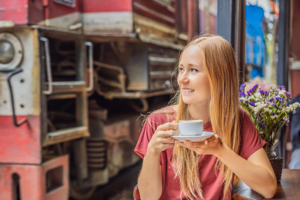 年轻的女游客坐在穿过河内市居民区的铁路旁喝着越南咖啡和鸡蛋。河内火车街是著名的旅游胜地。越南在冠状病毒隔离后重新开放图片下载