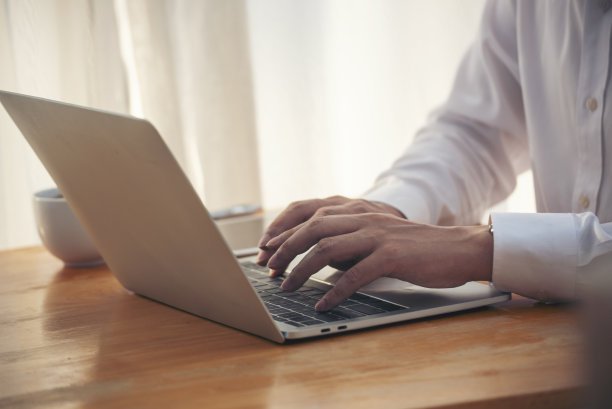 亚洲商人在办公桌前使用笔记本电脑。男手打字电脑键盘阅读财务图表策划分析市场数据。快乐的亚洲商人，在办公室工作的人图片下载